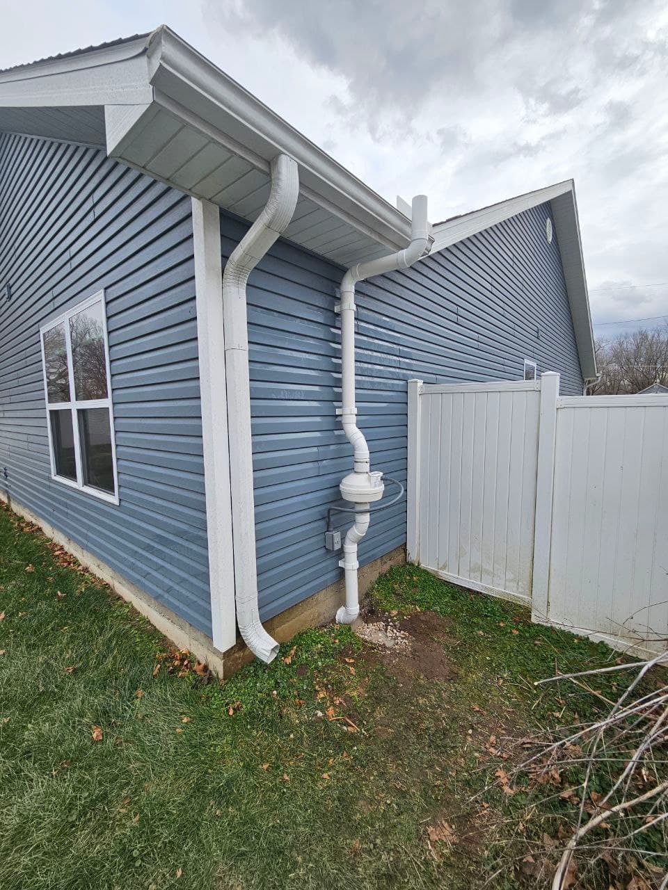 A radon mitigation system's vent pipe on the side of a house